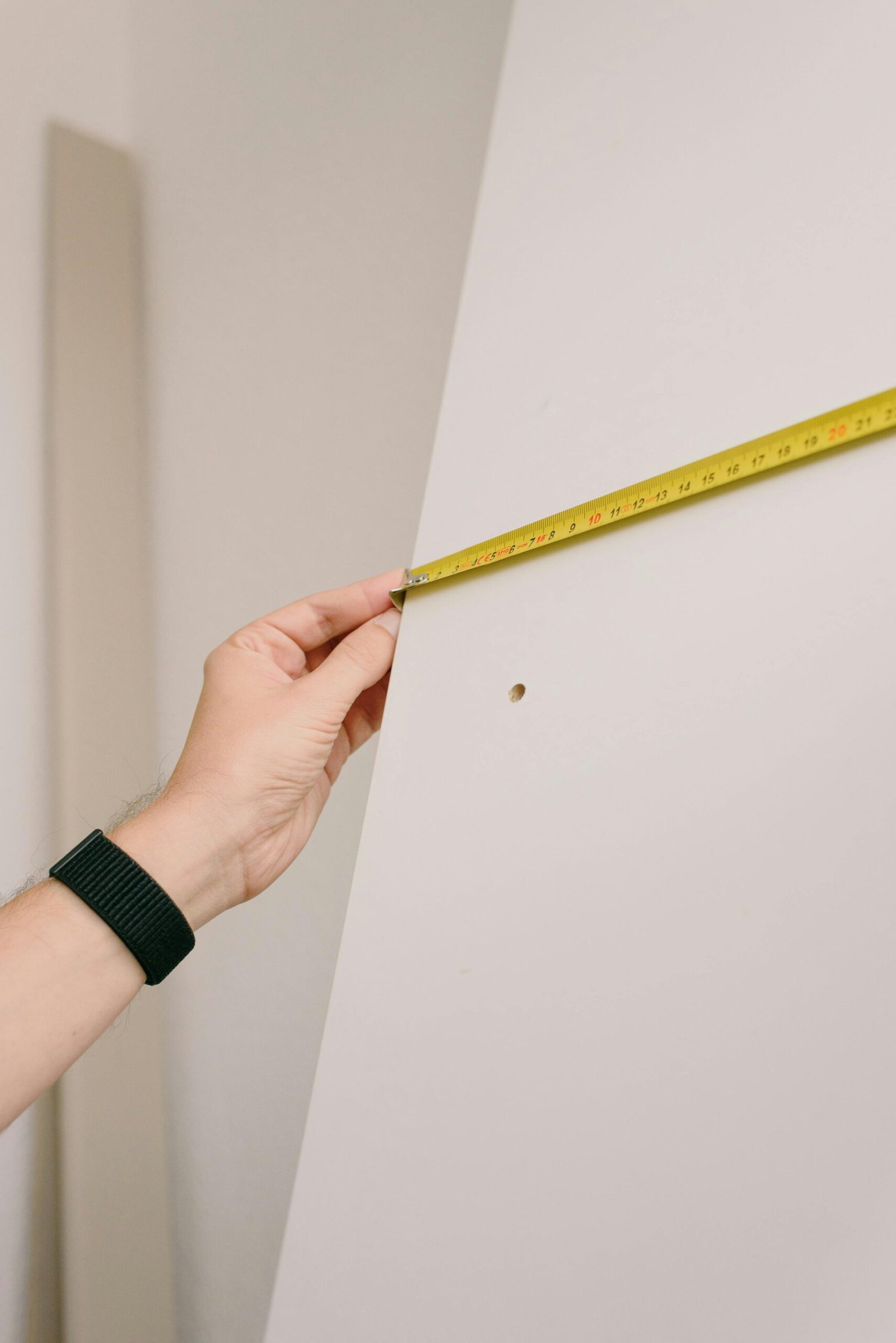 Close-up of a person measuring a wall with a yellow tape measure, perfect for home renovation or construction themes.